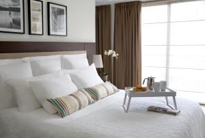 a bedroom with a white bed with a table on it at Sandy Beach Hotel & Spa - ex Sentido in Larnaca