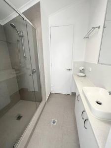 a white bathroom with a shower and a sink at Marlin Villa - Hervey Bay in Urangan