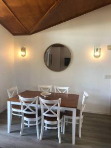 a dining room table with white chairs and a mirror at Marlin Villa - Hervey Bay in Urangan