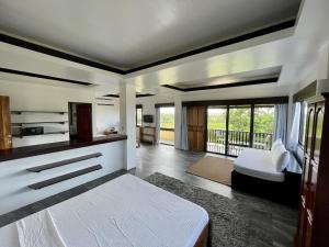1 dormitorio con cama blanca y balcón en Villa Maya, en General Luna