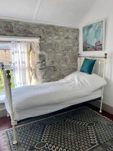 a bed in a room with a stone wall at The Painter’s Retreat in Lower Boscaswell