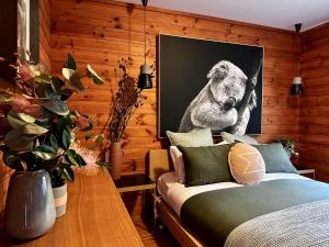 Kangaroo Valley Timber Cabin في كانجرو فالي: غرفة نوم بسرير وصورة للكولا