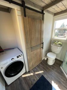 y baño pequeño con aseo y lavadora. en Delightful Tiny Home w/ 2 beds and indoor fireplace, en McKinleyville