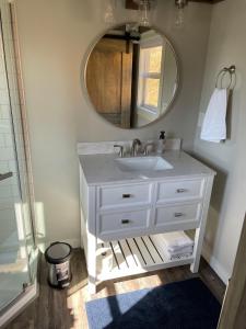 La salle de bains est pourvue d'un lavabo blanc et d'un miroir. dans l'établissement Delightful Tiny Home w/ 2 beds and indoor fireplace, à McKinleyville