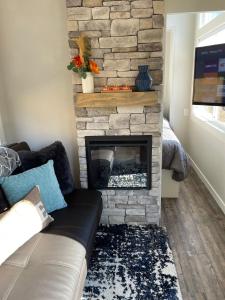 sala de estar con chimenea de piedra y sofá en Delightful Tiny Home w/ 2 beds and indoor fireplace, en McKinleyville