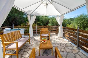 a patio with chairs and a table and an umbrella at Ria Sweet Home Paxos in Oziás