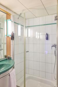 La salle de bains est pourvue d'une douche en verre et d'un lavabo. dans l'établissement ibis Baar Zug, à Zoug