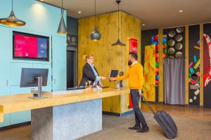 a man and a woman shaking hands at a counter at ibis Baar Zug in Zug