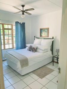 um quarto com uma grande cama branca e uma ventoinha de tecto em Unit 24 Pendleberry Grove Holidays em Bela-Bela
