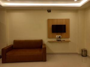 a waiting room with a couch and a tv on the wall at Hotel Ridley International in Digha