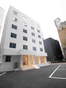 a large white building in a parking lot at Canvas Hostel in Busan