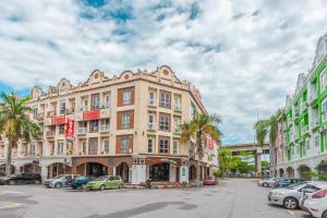 een groot gebouw met auto's geparkeerd op een parkeerplaats bij Hash House Hotel in Melaka