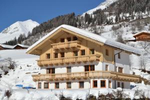 a building covered in snow with a mountain in the background at Apartment Santnerhof in Virgen