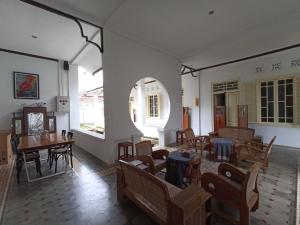 a room with tables and chairs and a room with windows at Mruyung Guest House Kota Lama Banyumas Mitra RedDoorz in Banyumas