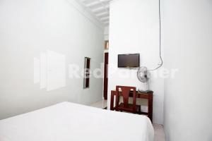 a white bedroom with a bed and a chair at Vania Guesthouse near RS Adam Malik Medan RedPartner in Medan