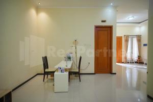 Zimmer mit einem Tisch, Stühlen und einer Tür in der Unterkunft One & Quin Guest House Syariah Mitra RedDoorz in Jenggrik