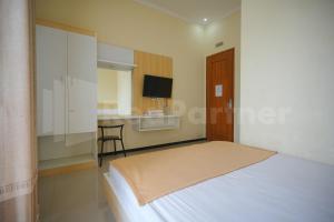 1 dormitorio con 1 cama y escritorio con silla en One & Quin Guest House Syariah Mitra RedDoorz, en Jenggrik