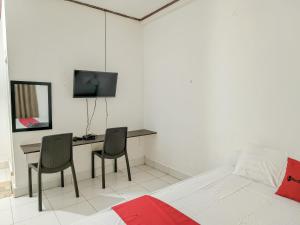 a bedroom with a bed and a desk with two chairs at RedDoorz @ Al Muhajir Homestay Kendari in Kendari