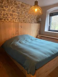 een bed in een kamer met een stenen muur bij GITE AU BORD DE L'AISNE in Érezée