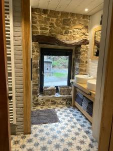 een stenen badkamer met een wastafel en een raam bij GITE AU BORD DE L'AISNE in Érezée