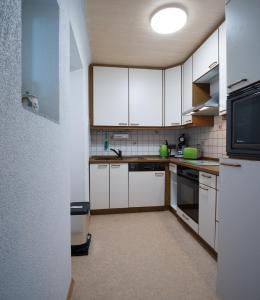 eine kleine Küche mit weißen Schränken und einer Mikrowelle in der Unterkunft Ferienwohnung „Prims“ in Wadern
