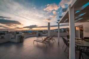 einen Balkon mit Stühlen, einem Tisch und einem Sonnenuntergang in der Unterkunft Home Sweet Home - Big Balcony with Great View in Kissamos