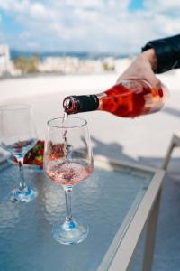 eine Person, die Wein in ein Glas auf einen Tisch gießt in der Unterkunft Home Sweet Home - Big Balcony with Great View in Kissamos