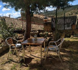 a table and two chairs sitting next to a tree at El Desván del Campanero apartamento con jardín in Murillo de Gállego