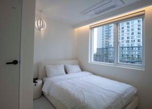 a bedroom with a white bed and a window at Canvas Hostel in Busan