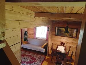 una sala de estar con sofá en una cabaña de madera en Leśniczówka, en Olszewnica Stara
