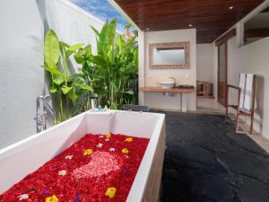 un baño con una bañera llena de cosas rojas en Avery Le Nixsun Villas Uluwatu by Waringin Hospitality, en Uluwatu