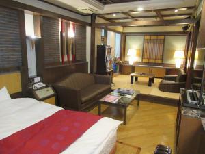 Habitación de hotel con cama y sala de estar. en Hotel Shuyukan (Adult Only), en Izumisano