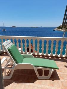 Apartments Uvala Murtar في يزيرا: كرسي أخضر وبيضاء على شرفة مطلة على المحيط