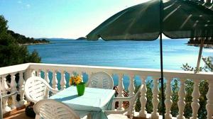 a table with a green umbrella on a balcony with the ocean at Apartments Uvala Murtar in Jezera
