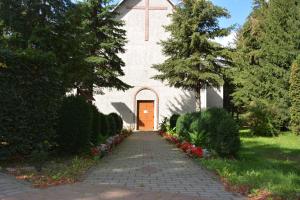 a church with a orange door and a brick walkway at Agroturystyka Staroscin in Rzepin