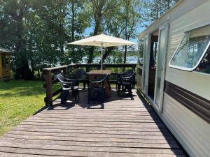 a deck with a table and chairs and an umbrella at Bajkowe Mazury Domek Holenderski PLAŻA ŁÓDKI KAJAKI WĘDKOWANIE in Mikołajki