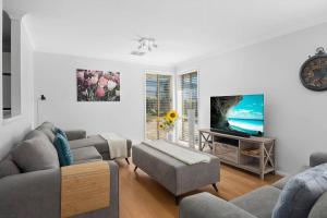 uma sala de estar com um sofá e uma televisão em The Scotty House - EV and pet friendly em Moss Vale