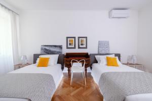 a bedroom with two beds and a table and a chair at ViandanteHome, Luxury Rooms in Trieste