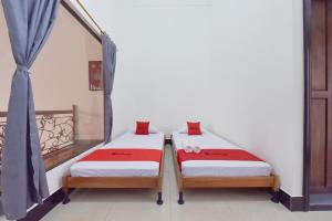 two beds in a room next to a window at RedDoorz Syariah near Dago Pakar 2 in Bandung