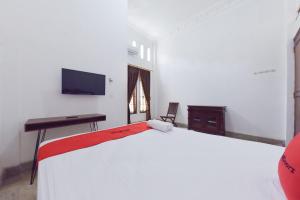 Dormitorio con cama, escritorio y TV en RedDoorz Syariah near Dago Pakar 2, en Bandung