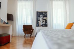 a bedroom with a bed and a chair and windows at ViandanteHome, Luxury Rooms in Trieste