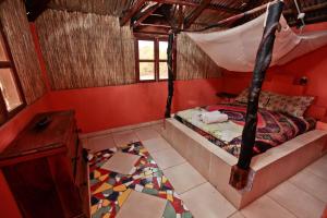 ein Schlafzimmer mit einem Bett in einem Zimmer mit roten Wänden in der Unterkunft Jinack Lodge in Jinack Island