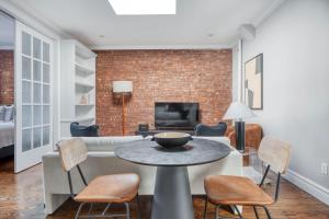 - un salon avec un mur en briques, une table et des chaises dans l'établissement UES 3br penthouse w gym wd nr Central Park NYC-1110, à New York