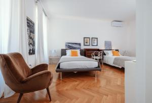 sypialnia z 2 łóżkami i krzesłem w obiekcie ViandanteHome, Luxury Rooms w Trieście