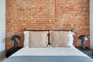 um quarto com uma parede de tijolos e uma cama com almofadas em UES 3br penthouse w gym wd nr Central Park NYC-1110 em Nova York