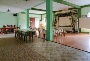 uma sala de jantar com paredes verdes e mesas e cadeiras de madeira em RedDoorz @ Star Jewel Lodge Apayao em Colonia Parcela Number One