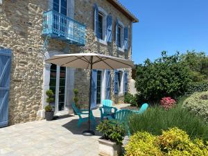 eine Terrasse mit 2 Stühlen und einem Sonnenschirm in der Unterkunft La Maison du Bonheur in Ausson