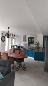 的住宿－Gîte aux trois suites parentales et son jacuzzi，厨房配有木桌和蓝色橱柜。
