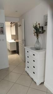 uma casa de banho branca com um vaso de flores numa cómoda em Gîte aux trois suites parentales et son jacuzzi 