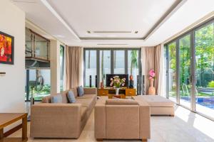 sala de estar con sofá, sillas y ventanas en Emblem Sea 2 bedroom villas, en Da Nang
